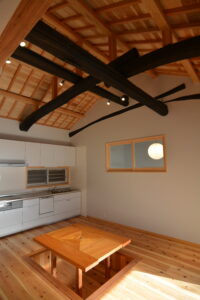 黒く加工した丸太梁が際立つ開放的なLDK